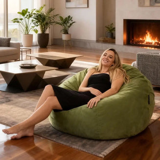 Woman sitting on a green bean bag in a cozy living room with a fireplace.