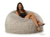 Woman sitting on a fluffy gray bean bag chair against a white background