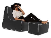 Woman sitting on a black bean bag chair with white trim against a white background