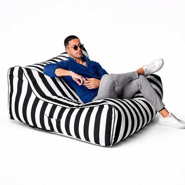 man posing on a black striped costa outdoor bean bag lounger by bean bags r us
