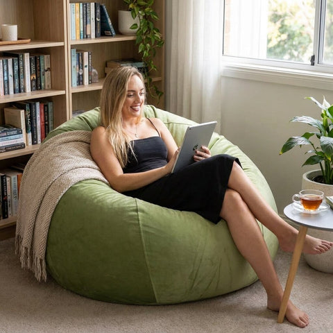lady sitting on a green velvet bean bag reading from her tablet