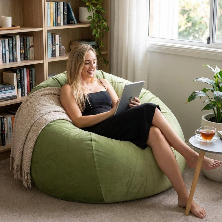 lady sitting on a green velvet bean bag reading from her tablet
