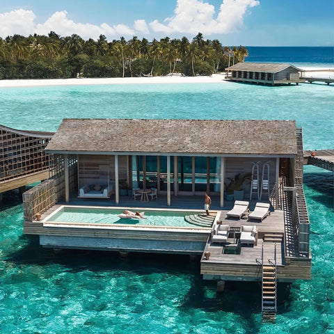 Aerial view of a Kudadoo Maldives Ocean Residence with a guest floating on a pool bean bag in the private infinity pool