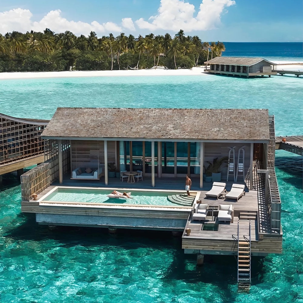 Aerial view of a Kudadoo Maldives Ocean Residence with a guest floating on a pool bean bag in the private infinity pool