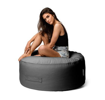 Woman sitting on a gray bean bag chair against a white background
