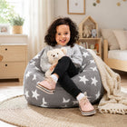 smiling young girl sitting on a grey bean bag chair with silver stars holding a teddy bear — thumbnail 3