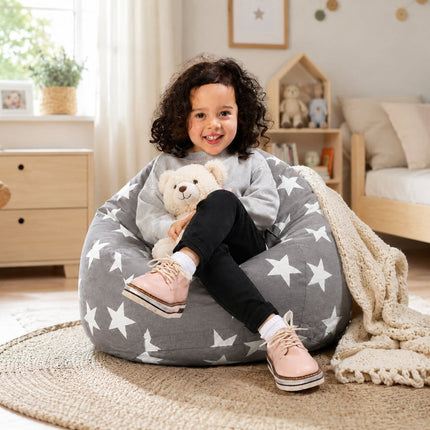smiling young girl sitting on a grey bean bag chair with silver stars holding a teddy bear
