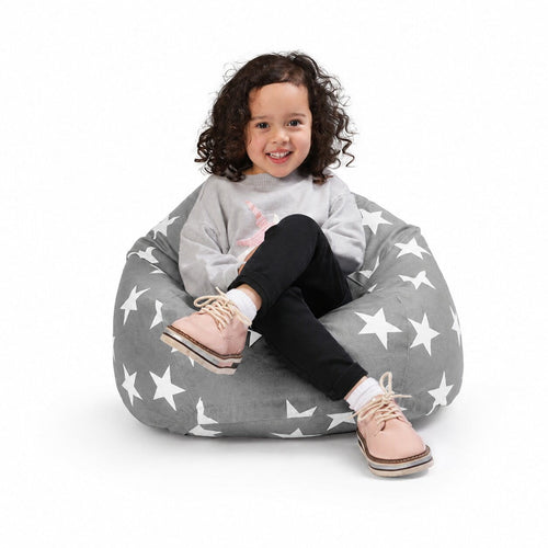 smiling young girl sitting on a grey bean bag chair with silver stars