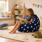 cute young boy sitting a on a blue beanbag with white stars reading a book — thumbnail 6