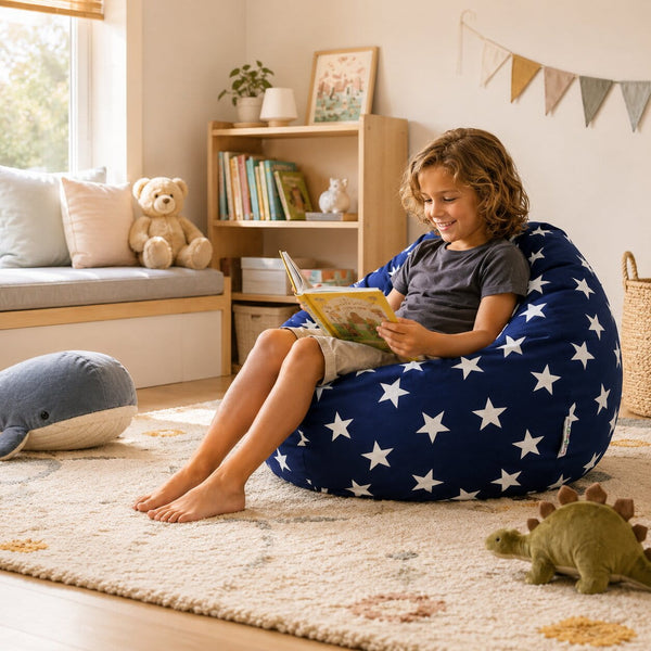 cute young boy sitting a on a blue beanbag with white stars reading a book — image 6