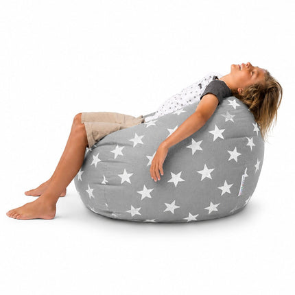 young boy laid back on a grey beanbag with silver stars