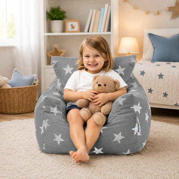 smiling young girl sitting on a grey bean bag chair with silver stars holding a teddy bear — image 4