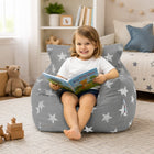 smiling young girl sitting on a grey bean bag chair with silver stars reading a book — thumbnail 5