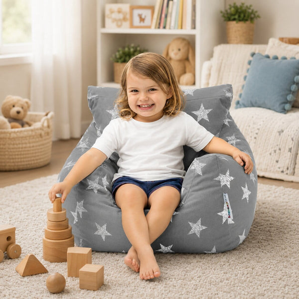 smiling young girl sitting on a grey bean bag chair with silver stars playing with wooden shapes — image 6