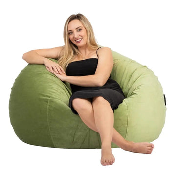 Woman sitting on a green bean bag chair against a white background