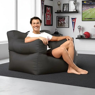 Person sitting on a large black bean bag chair in a room with sports memorabilia on the wall.