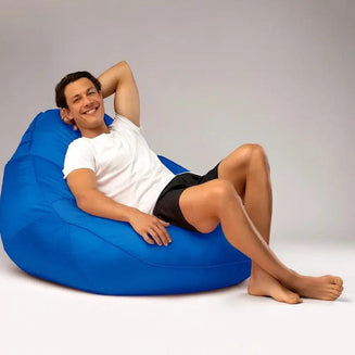 Man relaxing on a blue bean bag chair against a plain background