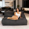 Woman sitting on a large gray bean bag in a modern living room.