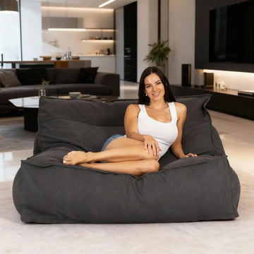Woman sitting on a large gray bean bag in a modern living room.