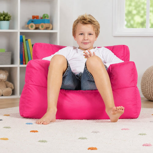 smiling young boy posing on a pink kids bean bag chair in a kids room