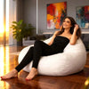 Woman sitting on a white bean bag chair in a modern living room with abstract art on the wall.