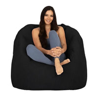 Woman sitting on a large black bean bag chair against a white background