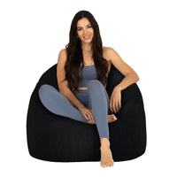 Woman sitting on a black bean bag chair against a white background