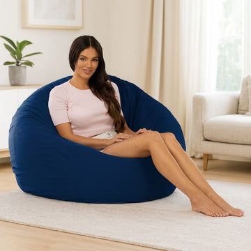 Woman sitting on a large blue bean bag chair in a living room.