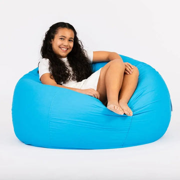 Child sitting on a blue bean bag chair against a white background