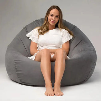 Woman sitting inside a large gray bean bag chair on a plain background