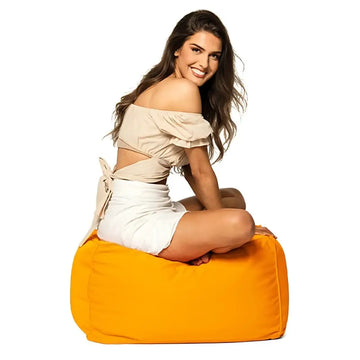 Woman sitting on a yellow bean bag ottoman against a white background