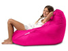 Young girl sitting in a bright pink bean bag chair on a white background