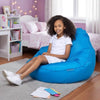Young girl sitting on a blue bean bag chair in a bedroom with pink walls and white furniture.