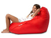 Person sitting on a red bean bag chair against a white background