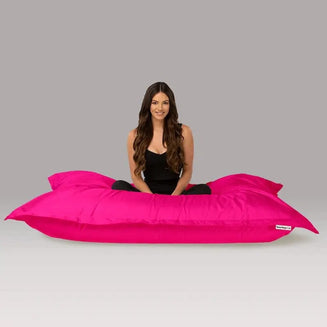 Woman sitting on a large pink bean bag against a gray background