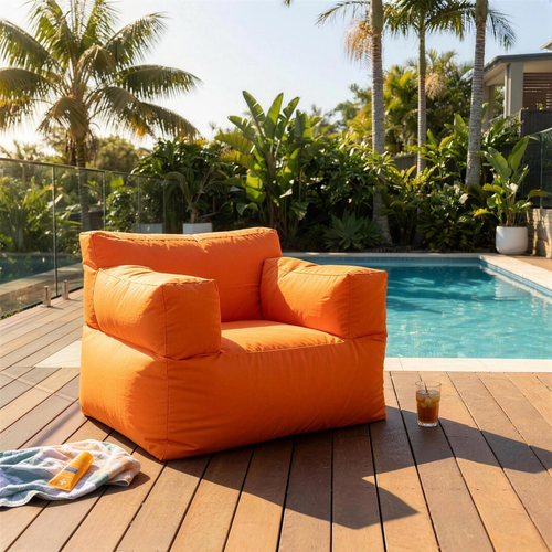 Orange Big Bob outdoor bean bag chair beside a backyard swimming pool on a sunny summer day
