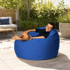 teen sitting on a blue outdoor bean bag in a courtyard — thumbnail 3