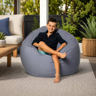 teen sitting on a grey outdoor bean bag in a courtyard — thumbnail 2