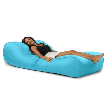 Woman lying on a blue bean bag sun lounge against a white background