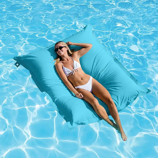 Woman lounging on a blue pool float in clear blue water