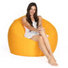 Woman sitting on a large orange bean bag chair against a white background