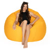 Woman sitting on a large orange bean bag chair against a white background