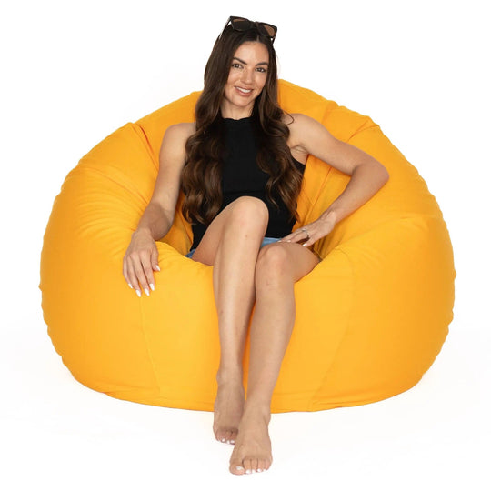 Woman sitting on a large orange bean bag chair against a white background