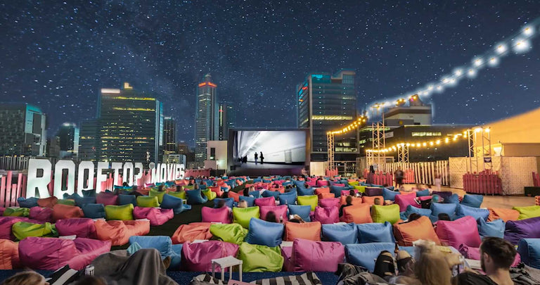 Outdoor movie screening with colorful chairs and city skyline in the background